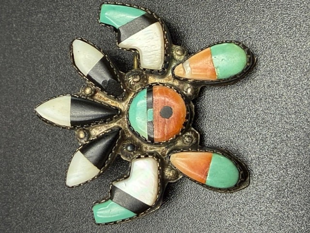 Handcrafted Sterling Silver Zuni Inlay Sunface Brooch: This brooch is a handcrafted sterling silver Zuni inlay sunface pin, likely dating from the 1930s to the 1950s. he design represents the Zuni Sunface symbol, a traditional deity figure characterized b