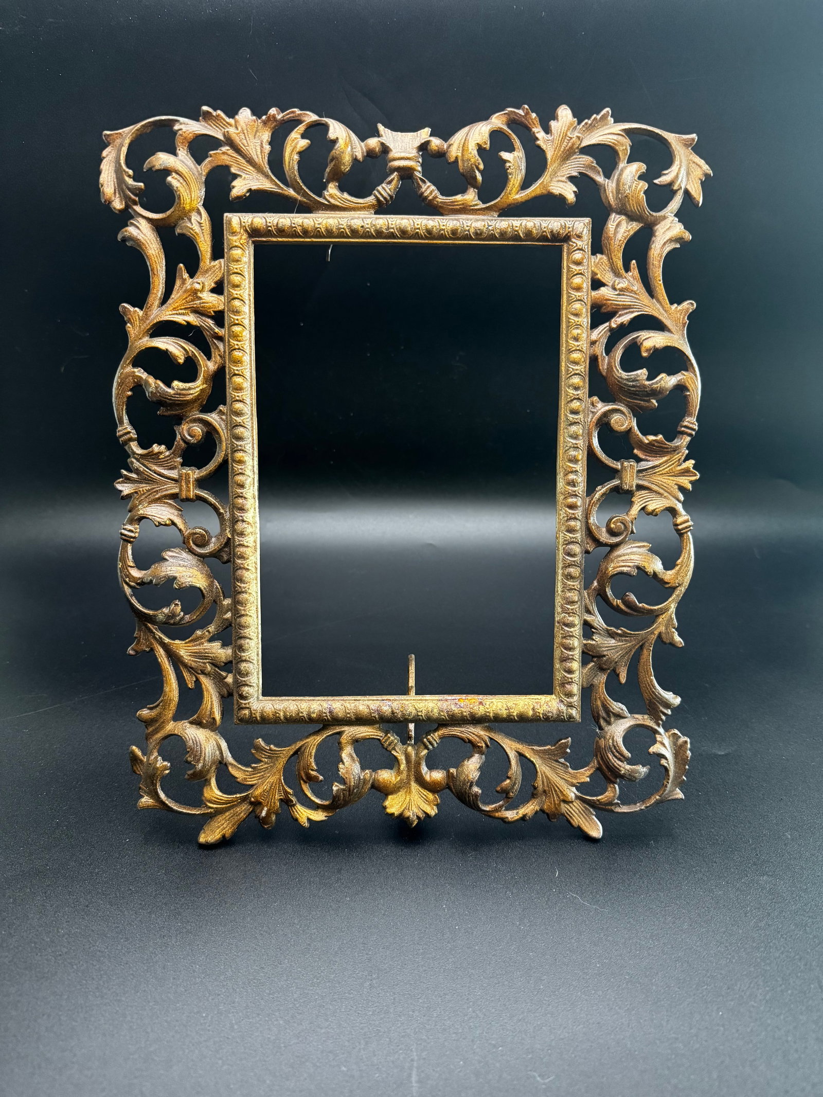 Antique Rococo Style Cast Metal Picture Frame: The elaborate, asymmetrical flourishes and organic flowing lines align with the Rococo Revival aesthetics popular during the late 19th and early 20th centuries. The frame is cast iron with an applied