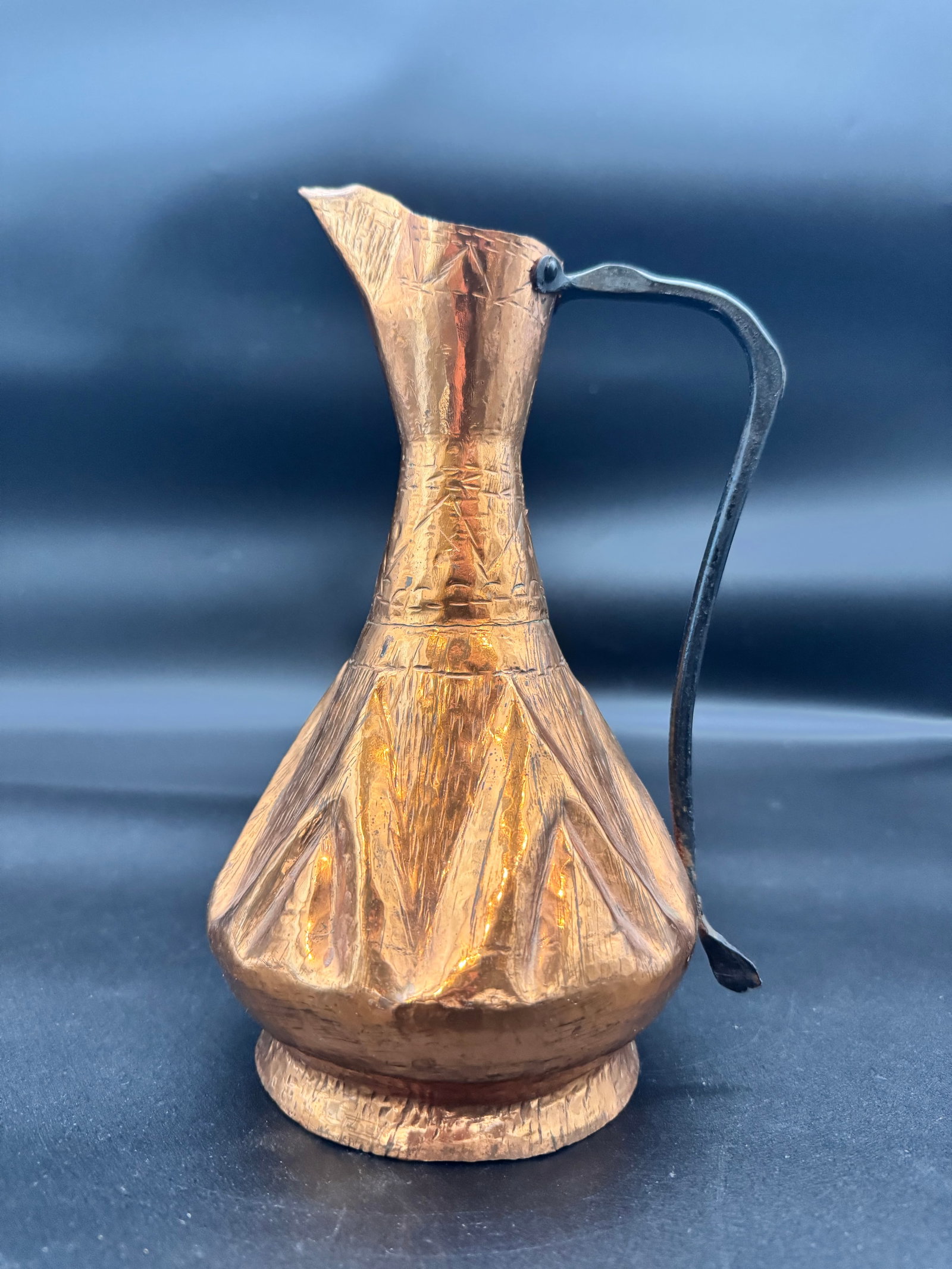 Handcrafted Antique Copper Pitcher: Handcrafted vintage hammered copper jug or pitcher possibly from Albania or Turkey featuring engraved decorative patterns and a metal hand forged handle. The hand-worked copper body shows visible hamm