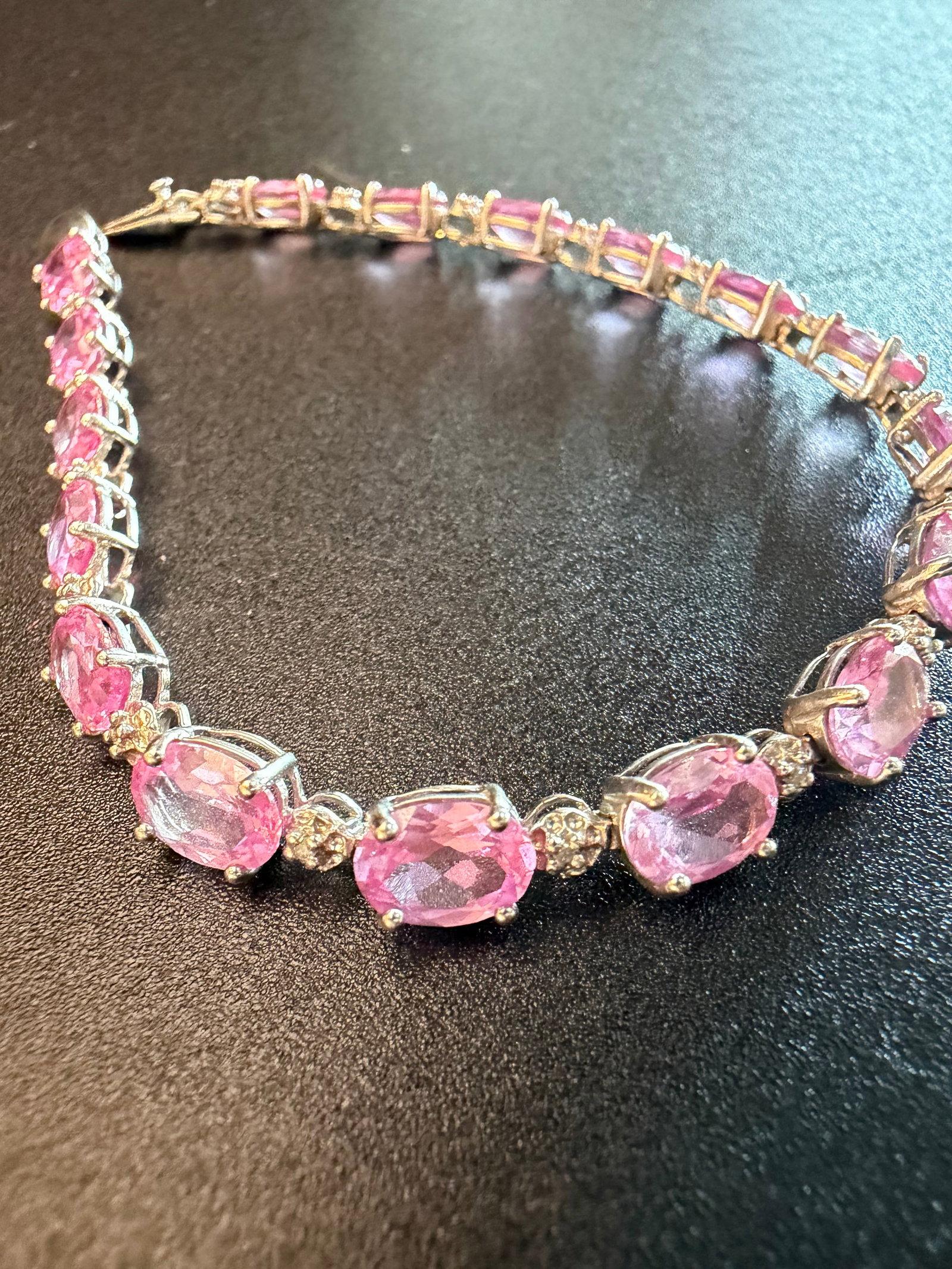 10K White Gold Tennis Bracelet: 10K white gold tennis bracelet set with oval pink stones, weighing 8.1 grams and measuring 7 inches long.
