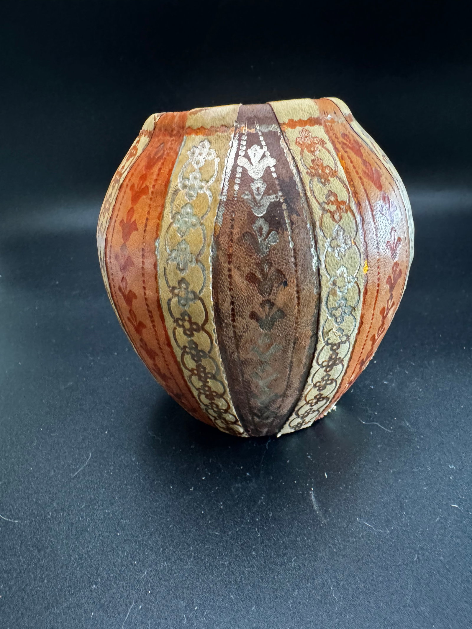 Handcrafted Leather Covered Vase: Handcrafted leather-covered vase decorated with stamped, silver-colored and gold filigree patterns. Vases of this nature are frequently used for decorative purposes rather than utilitarian water
