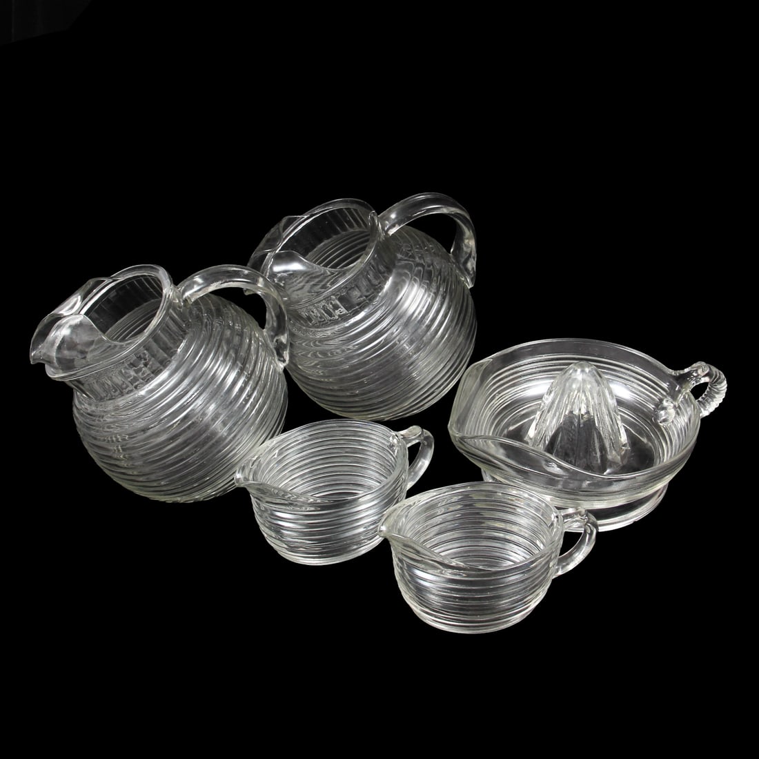 Anchor Hocking "Manhattan" Serving Pieces: A collection of serving pieces by Anchor Hocking in the "Manhattan" pattern. Included in the lot is 2 pitchers, 1 juicer, and 2 creamer pitchers. 6w, 6h, 5d inches.