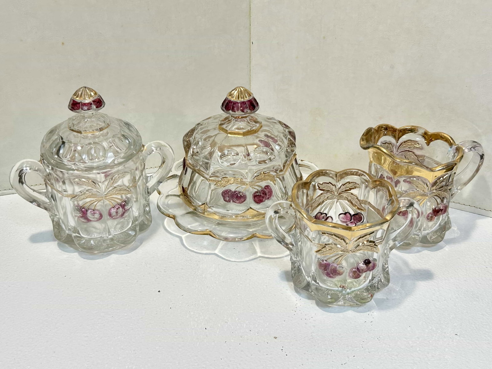 Antique Northwood Glass Cherry Cable 4 Piece Table Set: Northwood Glass 4pc table set including covered butter, creamer, covered sugar, and spooner/waste jar. Condition is good w/ no visible chips or cracks. Some wear on red and gold paint.