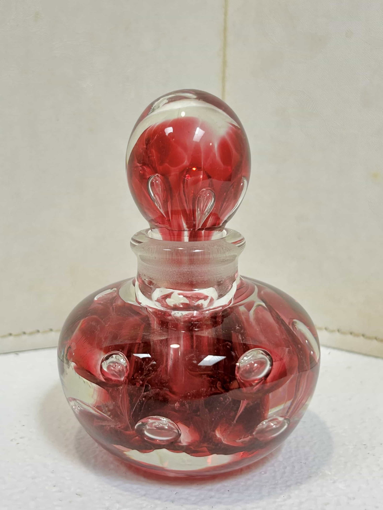 Joe St. Clair Art Glass Perfume Paperweight w/ Stopper: Beautiful cranberry swirl throughout the glass, controlled bubbles, ground stopper, measures 4.5" tall. It is in good condition with no chips or cracks.