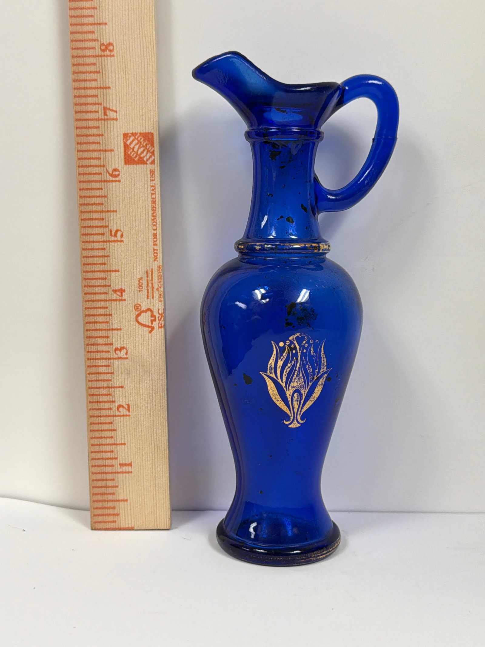 Vintage Avon Cobalt Blue Glass Persian Pitcher Decanter with Gold Gilt Tulip Accent (circa 1974): An authentic vintage 1970s Avon decorative glassware piece, originally produced to hold bath oil or cologne. This elegant, Greek/Persian-style ewer features deep cobalt blue glass, an integrated loop 