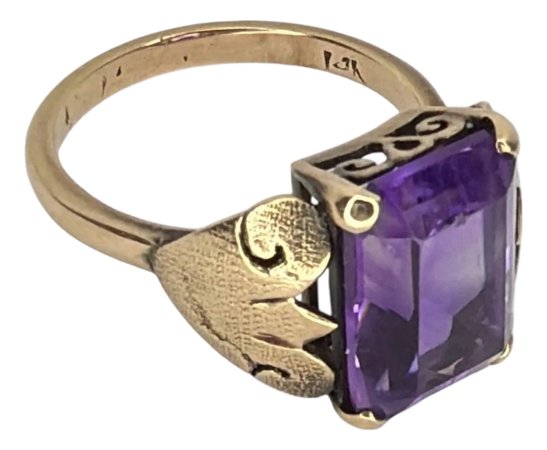 Art Deco 14k Gold Emerald-Cut Amethyst Ring: Sculptural Art Deco 14K Gold Amethyst Ring. Stone is in an emerald cut and measures approximately 12mm x 11mm, securely set in a four-prong mount. The shoulders are modeled with foliate motifs, a