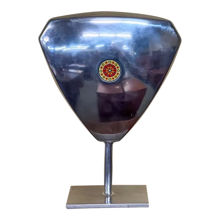 Aluminum Sculpture With Glass Disc From 1971: Aluminum sculpture with a colorful round glass insert on the front and back center. The glass discs are painted with small dots in yellow, green, red, and blue. It is not quite triangular in shape