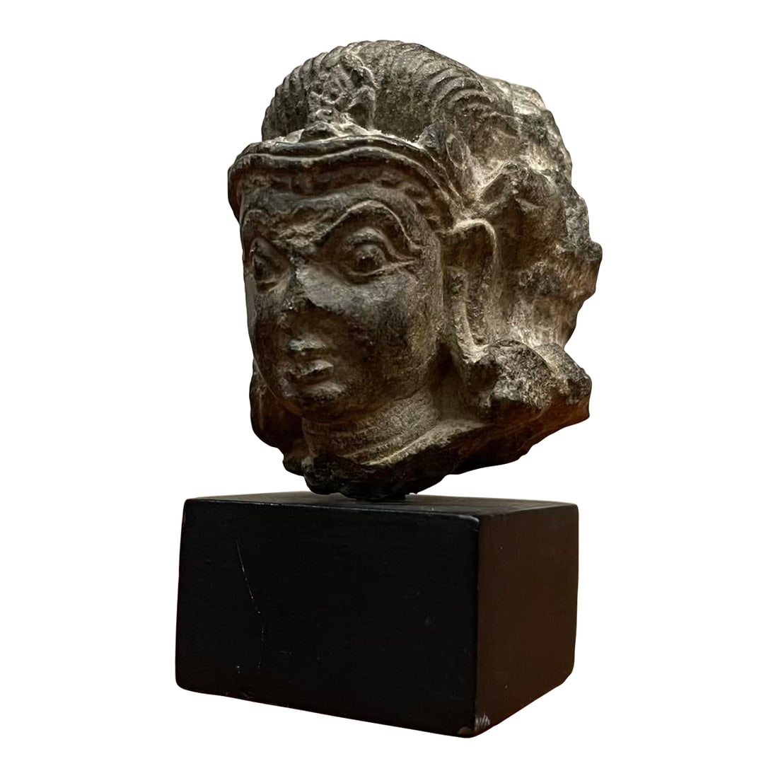 Petite 12th Century Nepalese Temple Fragment Sculpture on Stand: A petite and expressive temple fragment from 12th-century Nepal, likely depicting Vishnu or a related deity. This intricately carved head was once part of a larger temple sculpture and retains a