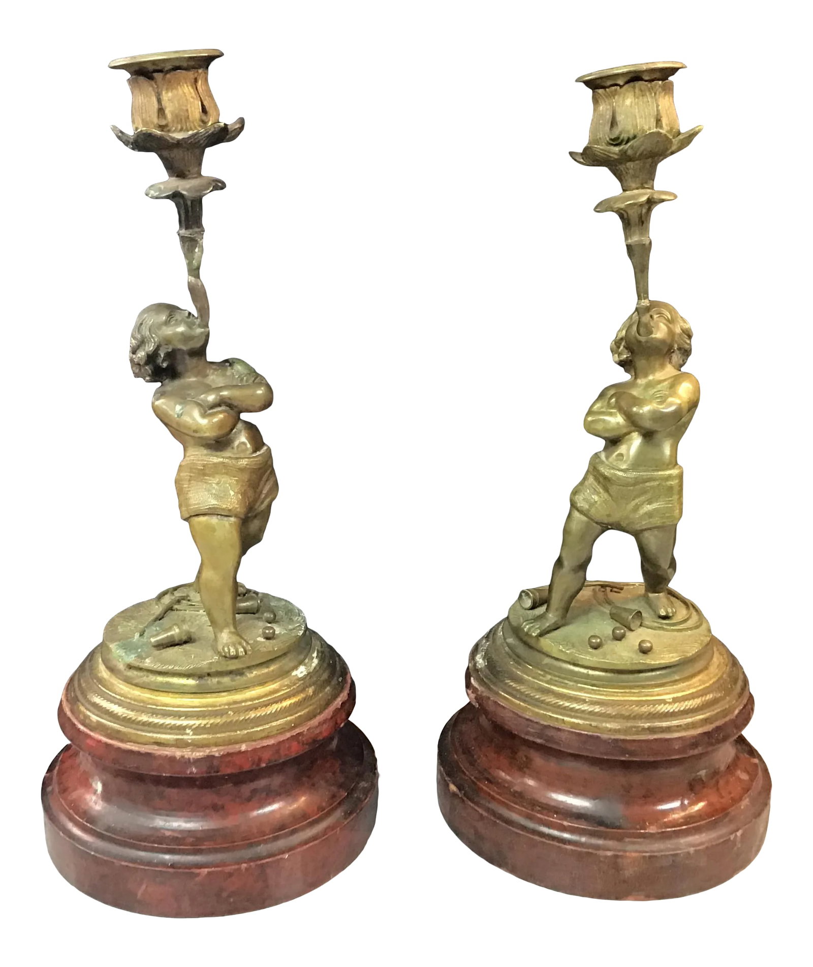 Late 19th Century Continental Bronze Boy Acrobat Candleholders- a Pair: A fine pair of European bronze candlesticks with boy acrobats balancing candle holders in their mouth. An assortment of items spread out on the ground around them. Mounted on faux porphyry wood