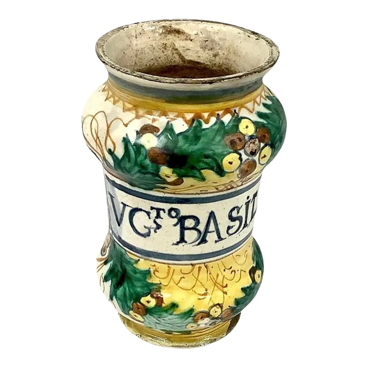 17th Century Italian Faience Apothecary Jar: 17th Century Italian Faience ceramic apothecary jar. Bright colors of yellow, green and dark blue on cream background. In writing is "VG To BASILICO". There is a label affixed to bottom that states,