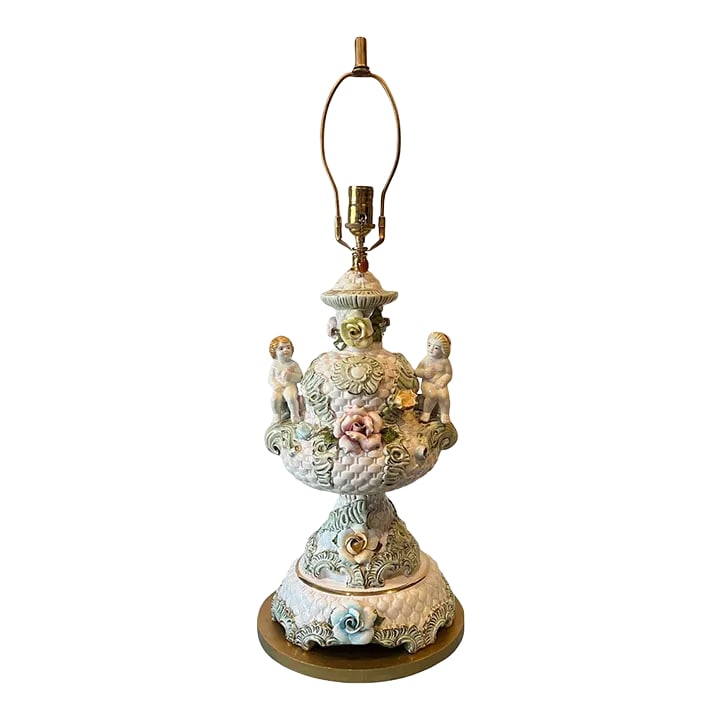 Mid-Century Capodimonte Porcelain Cherub Basketweave Floral Table Lamp: This exquisite Capodimonte porcelain table lamp is a masterpiece of artistry and elegance. Its grand urn-shaped body, rendered in a soft antique white, serves as a canvas for intricate detailing. Play