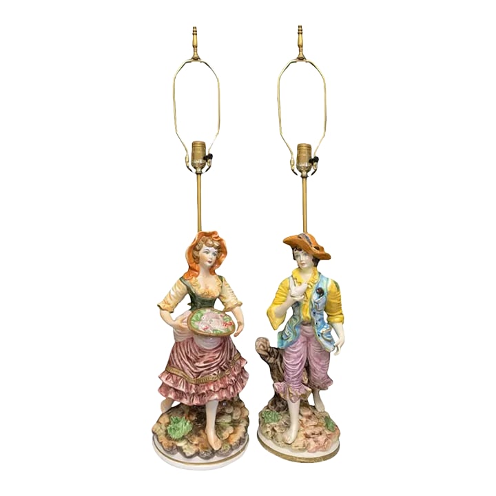 Mid-Century Capodimonte Porcelain Table Lamp- Villagers: Young Man and Lady-A Pair: These exquisite Capodimonte Porcelain lamps showcase the skill of Italian artisans through their meticulous craftsmanship. The set features two endearing young villagers, a girl and a boy, each dresse
