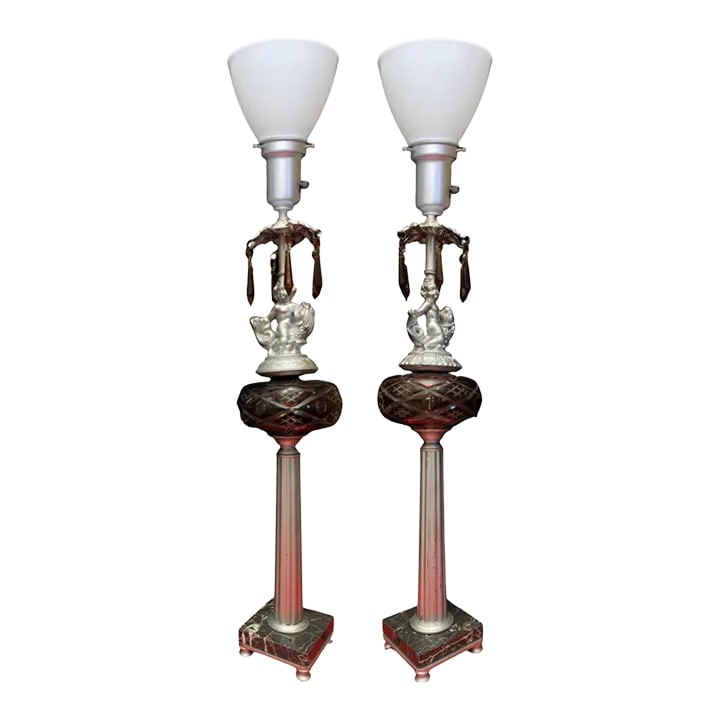 Vintage Putti Riding a Fish - Torchiere Column Lamp- a Pair: Each lamp features a captivating silver-tone putti joyously astride a fish serpent. The putti's left hand firmly grips the serpent's head while his right hand clasps its intricately twisted tail. His 