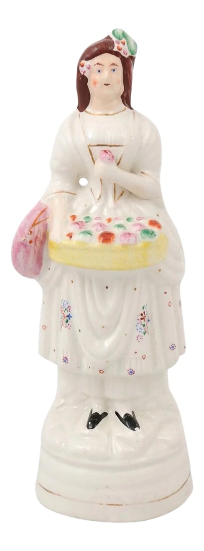 Mid 20th Century Small English Porcelain Decorative Figurine Depicting Lady with Floral Basket: A small English porcelain decorative object depicting a lady carrying a floral basket. Created in England during the 20th century, this petite sculpture depicts a young lady, dressed in white with