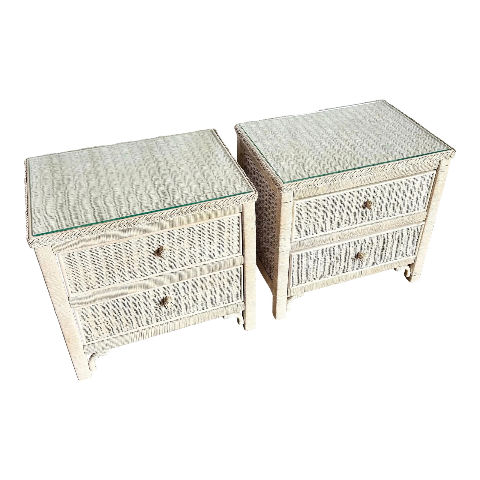 Vintage Boho Chic White Washed Wicker Glass Top Nighstands - A Pair: A charming pair of Boho Chic nightstands, beautifully crafted in white-washed wicker with braided trim and original glass tops. Each features two spacious drawers with woven knobs and classic coastal