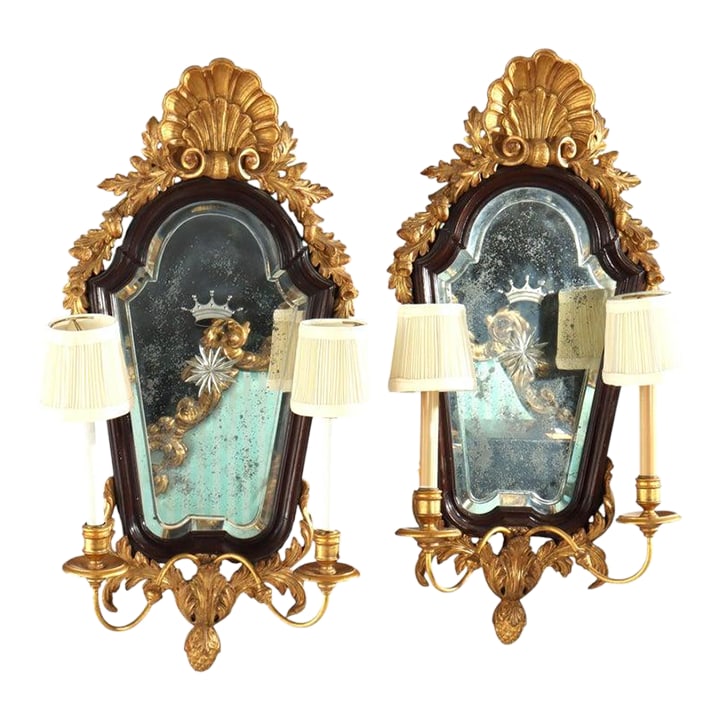 Pair 30" English Carved Mahogany & Gilt Wood Mirrored 2-Light Wall Sconces C1840: This pair of antique English mirrored sconces, dating to approximately 1840, exemplifies the opulent aesthetic of the early Victorian era with strong Georgian influences. Crafted from richly carved ma