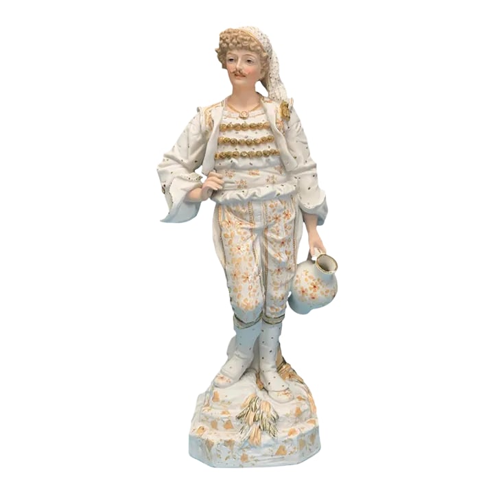 15 Inch Tall Antique French Bisque Porcelain Man Holding a Water Jug: This bisque porcelain figurine stands at 15 inches tall and portrays a young man in a moment of pause during his journey to fetch water. He is dressed in 19th-century French period clothing meticulous