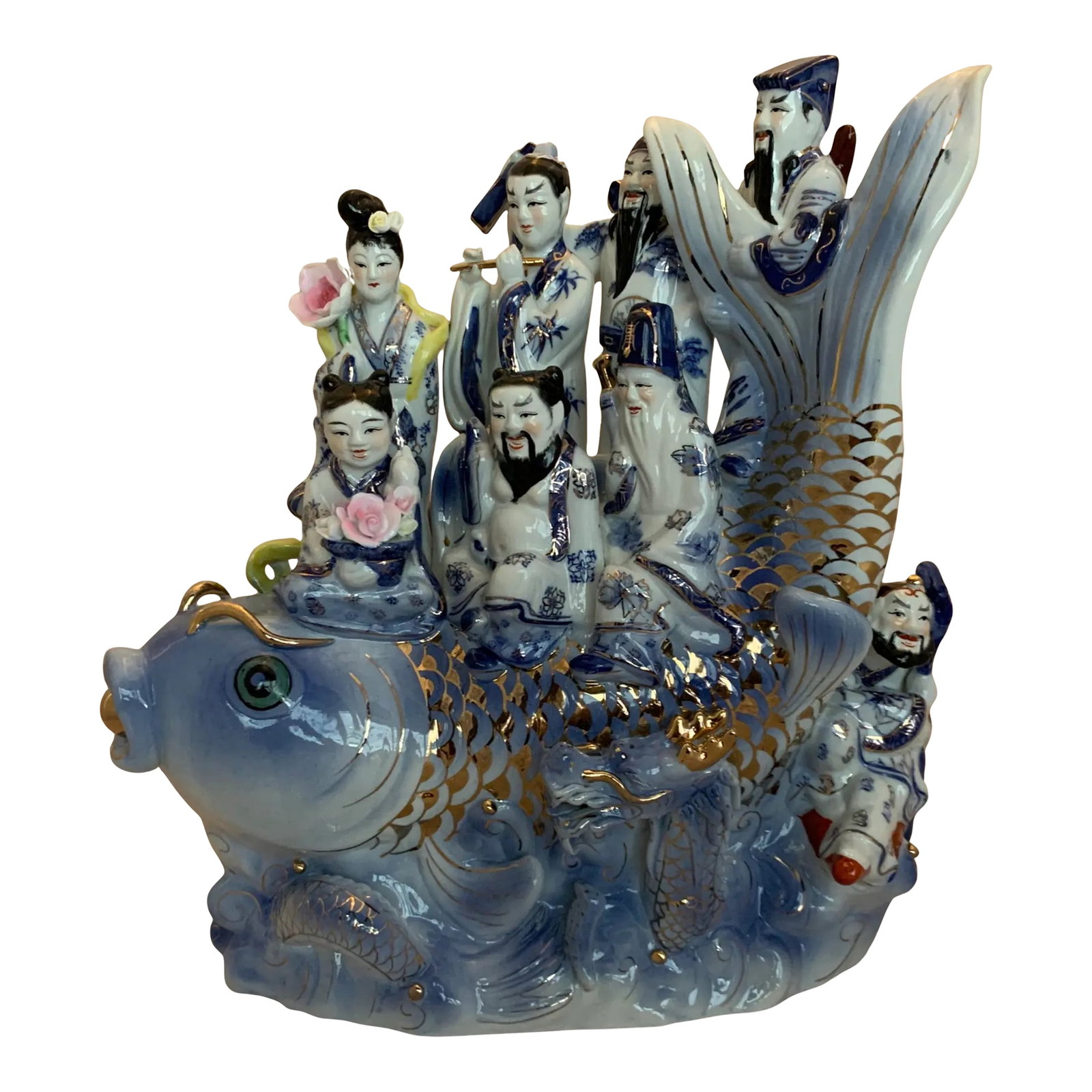 Chinese Deities Koi Fish Porcelain Sculpture: This 18-inch-tall porcelain sculpture beautifully depicts the legendary tale of the Eight Immortals from Chinese mythology. Shown crossing the turbulent East Sea atop a giant koi fish, the scene symbo