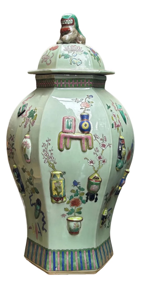 Vintage Chinese Light Celadon Green Relief Motif Hexagonal Porcelain Jar: This impressive hexagonal baluster-form ginger jar is finished in a serene celadon green glaze, serving as a soft backdrop for its elaborate famille rose ornamentation. The vessel is meticulously deco
