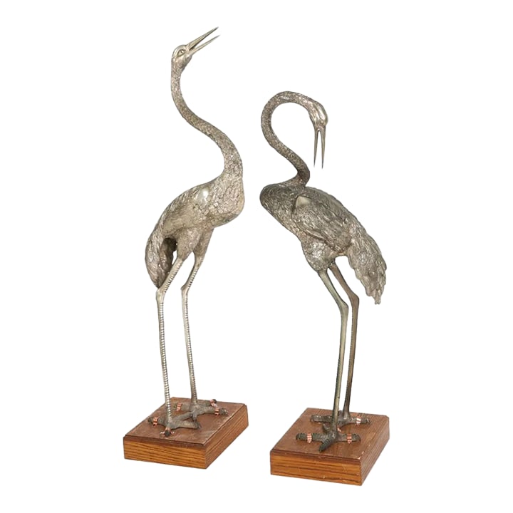 Monumental Pair of Silvered Crane Sculptures on Wooden Plinth Bases | 20th Century: A striking and highly decorative pair of monumental crane sculptures, executed in silvered metal—likely silvered bronze or brass—and mounted upon custom hardwood plinth bases. Capturing