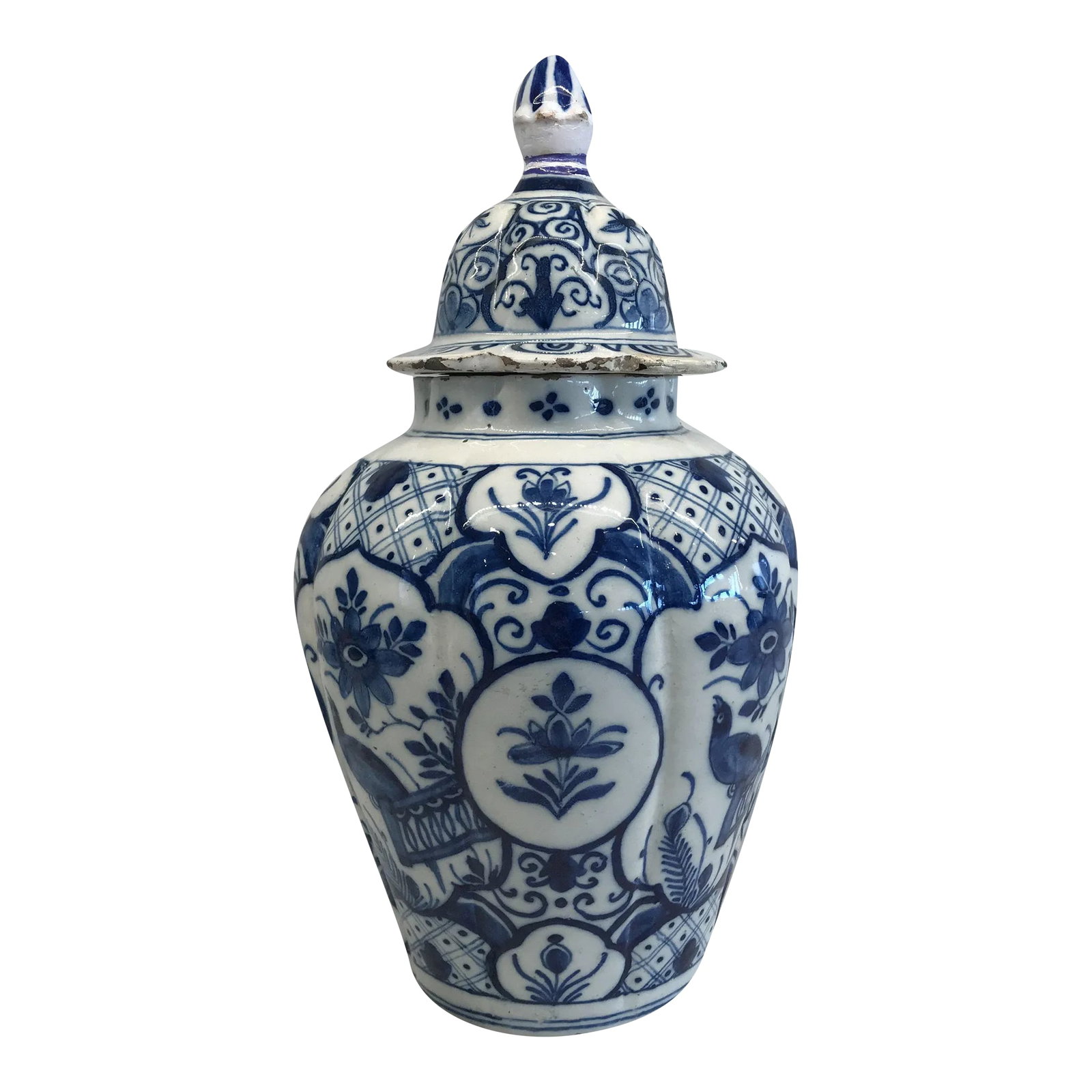 Delft Blue and White Vase With Top: A Delft blue and white covered vase decorated with blue flowers. The cover is topped by a traditional ball finial. The back of the vase is decorated with a single Artemisia leaf. Small edge chips rest