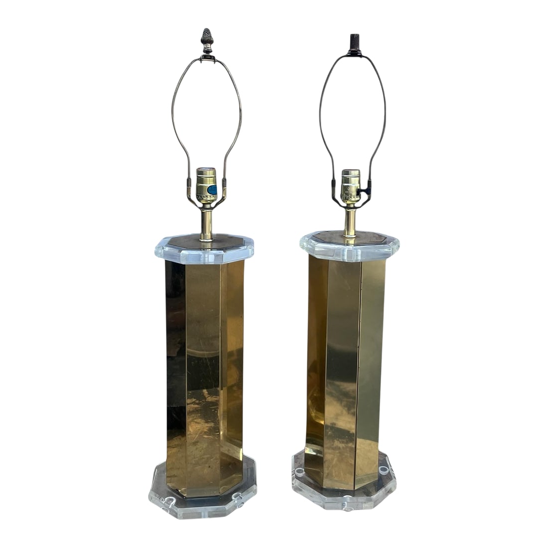 1970s Brass & Lucite Table Lamps - Set of 2: Pair of octagonal Brass / Steel table lamps with lucite base and top. American wired with harps and finials. ( No Shades) Condition: Alterations: Original Condition Unaltered Imperfections: Some Imper