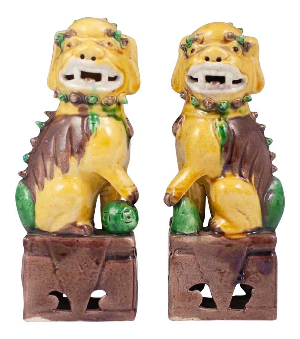 20th Century Chinese Sancai Glazed Porcelain Foo Dogs - a Pair: A pair of pottery Sancai glazed ceramic foo dogs.Garnished with yellow, green, and purple toned glazes. Marked:"China" along the underside. CIRCA: Early-Mid 20th century. Condition: Alterations: