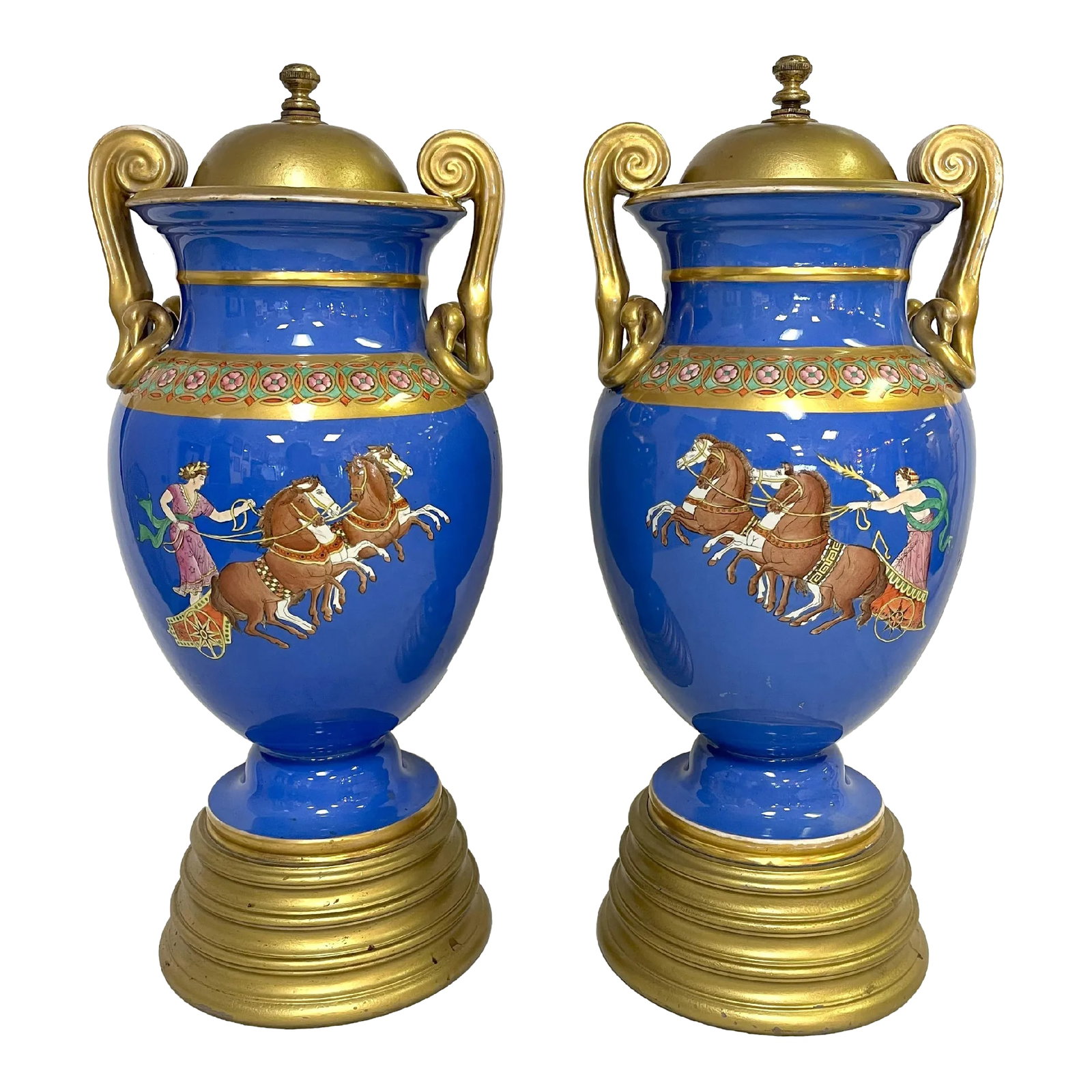 Early 20th Century European Neoclassical Hand Painted Blue Porcelain Urns With Chariot Scenes- a Pai: Cool pair of European Neoclassical hand painted porcelain urns from the 1920's. Each has a blue background with different chariot scenes and warrior busts on the other side. There are painted gold