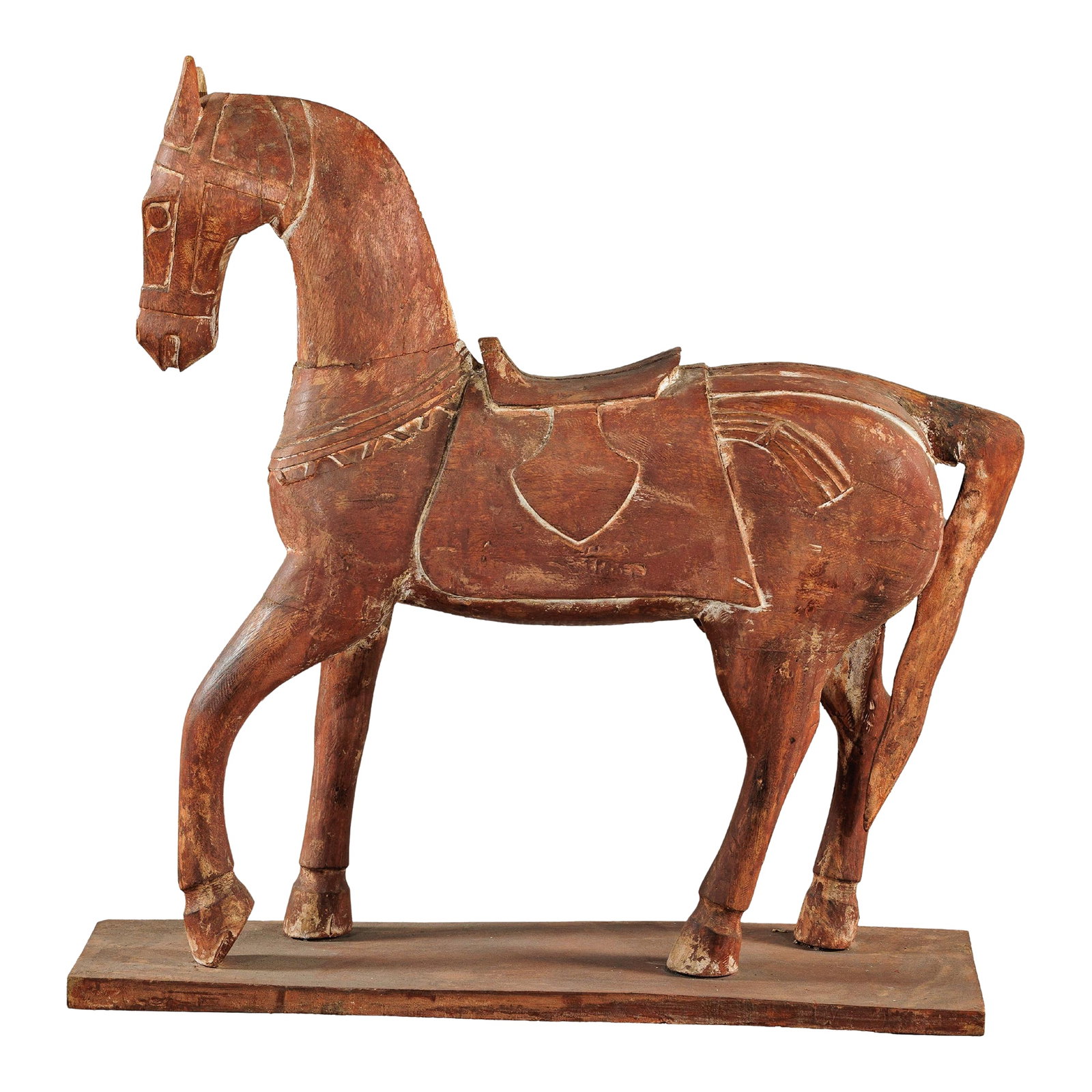Circa 1950 Rustic Vintage Carved Wood Horse with Saddle on Stand: A rustic vintage wooden horse carving, presented on a flat base and adorned with a carved saddle and harness details. The figure is hand-carved with a stylized, almost folk-art quality, its elongated