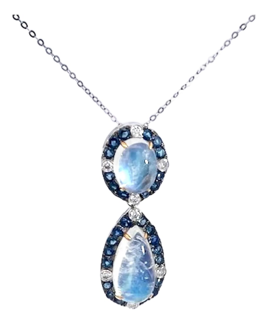 Double Drop Moonstone Pendant W/Diamonds and Sapphires 18k: This enchanting double-drop pendant necklace showcases a dreamy, ethereal quality with two luminous cabochon moonstones suspended from a delicate white gold chain. The upper stone features a smooth