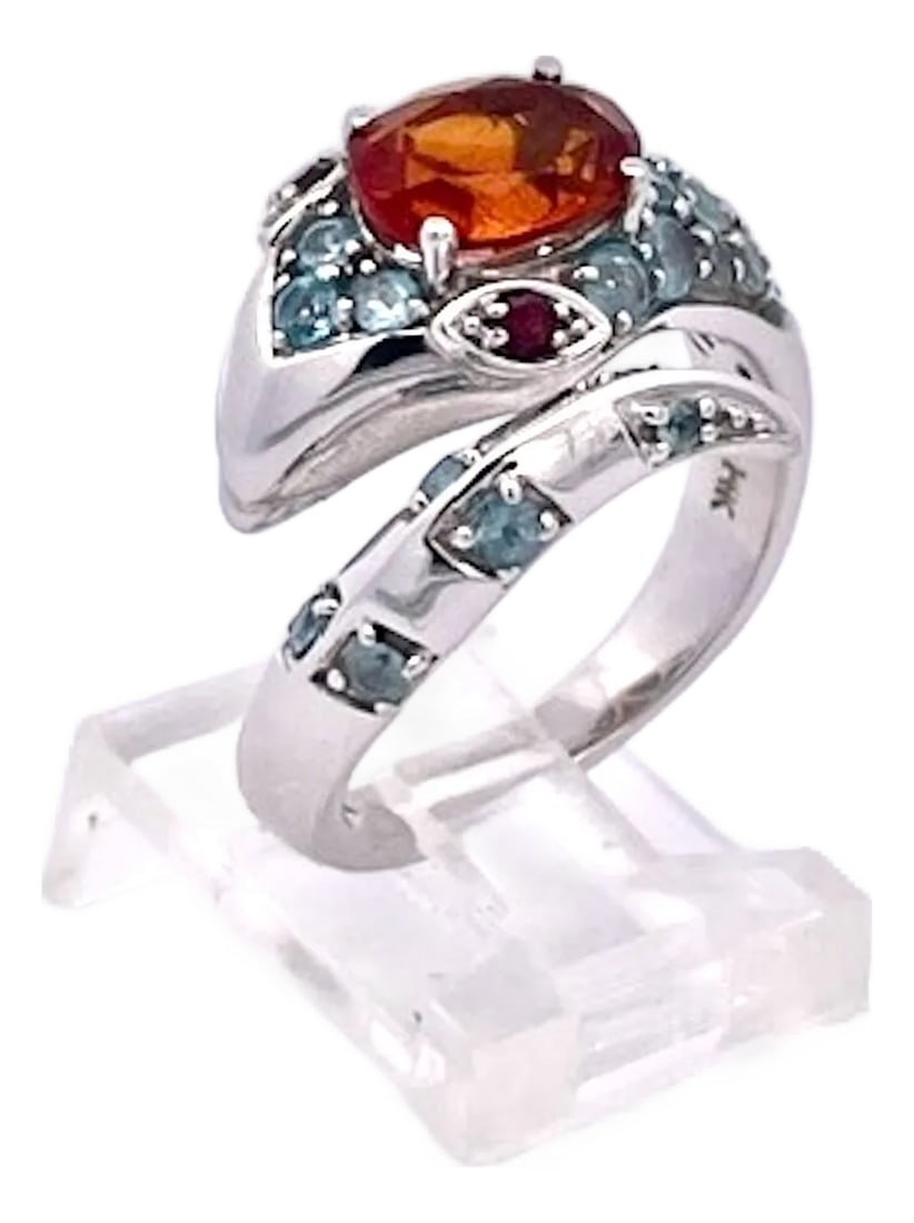 1970s Polished 14k White Gold Garnet and Ruby Cocktail Ring With Blue Topaz, Size 5: This striking cocktail ring features a bold wraparound serpentine design in polished white gold. At its crown sits a vibrant oval-cut garnet, glowing in rich amber-orange tones, held securely in a