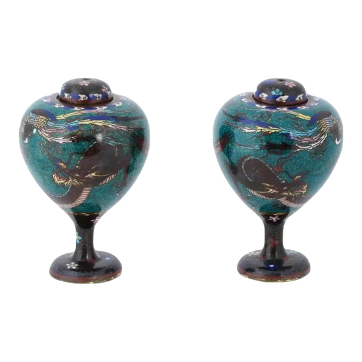 Antique Pair of Japanese Cloisonne Enamel Dragon and Phoenix Bird Jars: A pair of antique Japanese Early Meiji period vases, characterized by their oval shape tapering downward, mounted on stems, and adorned with matching covers. The surfaces of these vases feature