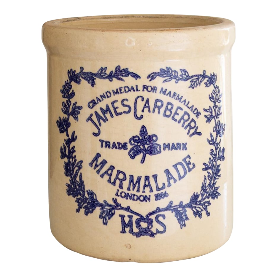 James Carberry London Ceramic Stoneware Marmalade Crock Half Gallon: This half-gallon James Carberry London marmalade crock features a cream-colored glaze that leans towards a soft butter yellow, but is more muted. The blue text is bordered with a garland and reads
