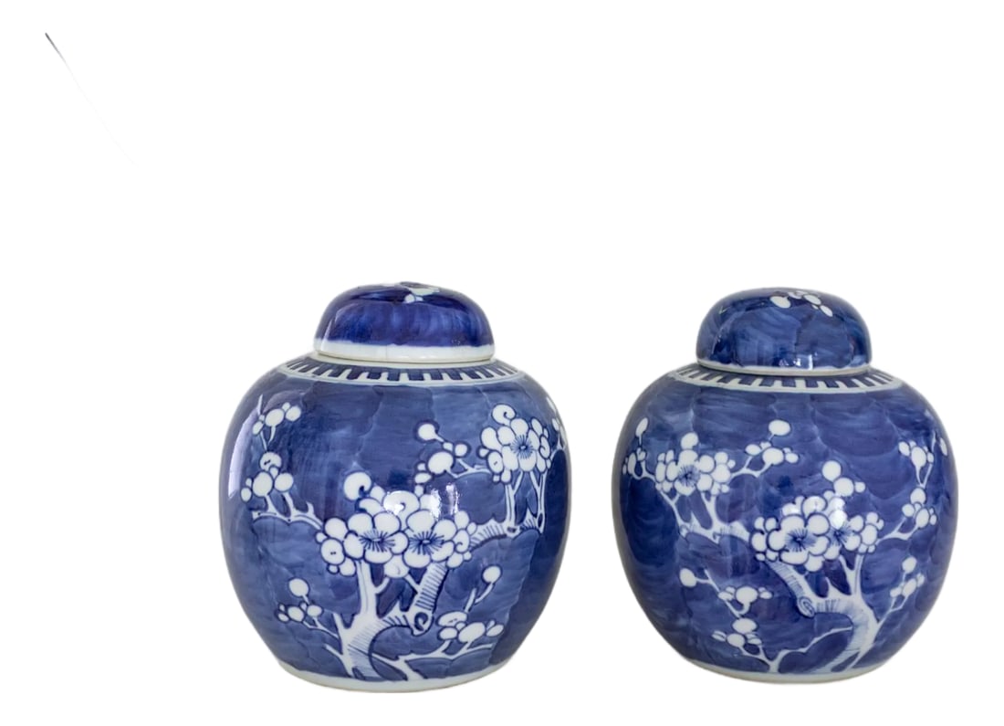 Pair of Blue and White Chinese Chinoiserie Prunus Blossom Lidded Ginger Jars: A lovely pair of vintage blue and white chinoiserie lidded ginger jars features a short, rounded melon form with domed lids. Each jar is hand-painted with traditional plum/prunus blossoms and