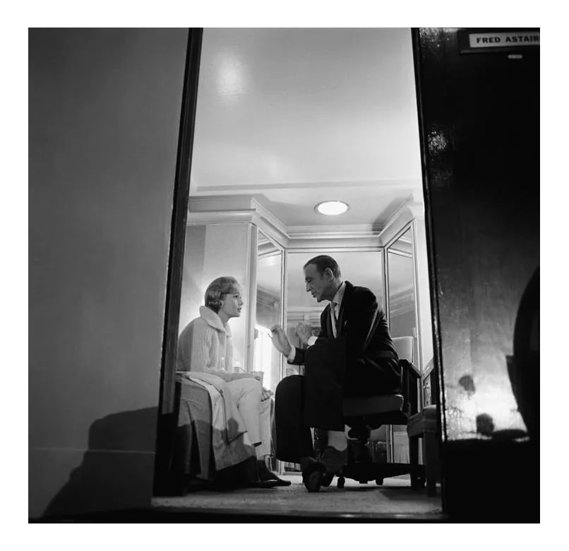 Debbie Reynolds Talking With Fred Astaire 1960: Debbie Reynolds talking with Fred Astaire in his dressing room during a break in filming "The Pleasure of His Company," 1960. 11" x 14" silver gelatin fiber based print signed on verso by the
