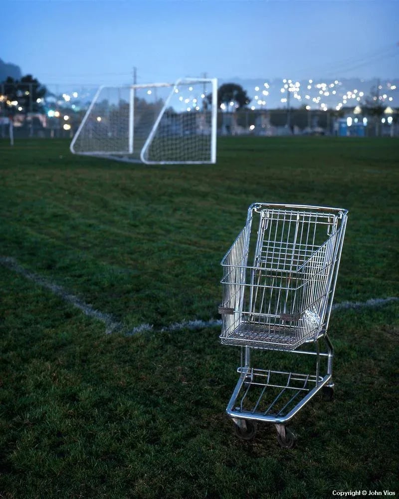 Contemporary Night Photograph "Shopping Cart" by John Vias: Note from the artist, John Vias: "The similarity of pattern and structure of the shopping cart and the goal net drew me to this scene." This 14" x 11" archival color photograph is presented in a 20"