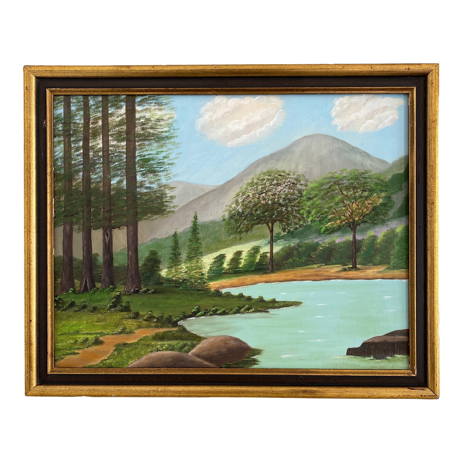Vintage Folk Art Tranquil Landscape Oil on Canvas Framed Painting: Vintage folk art tranquil landscape oil on canvas painting depicting a natural scene with evergreen trees, a body of water, a light blue sky with white puffy clouds, and mountains in the background.
