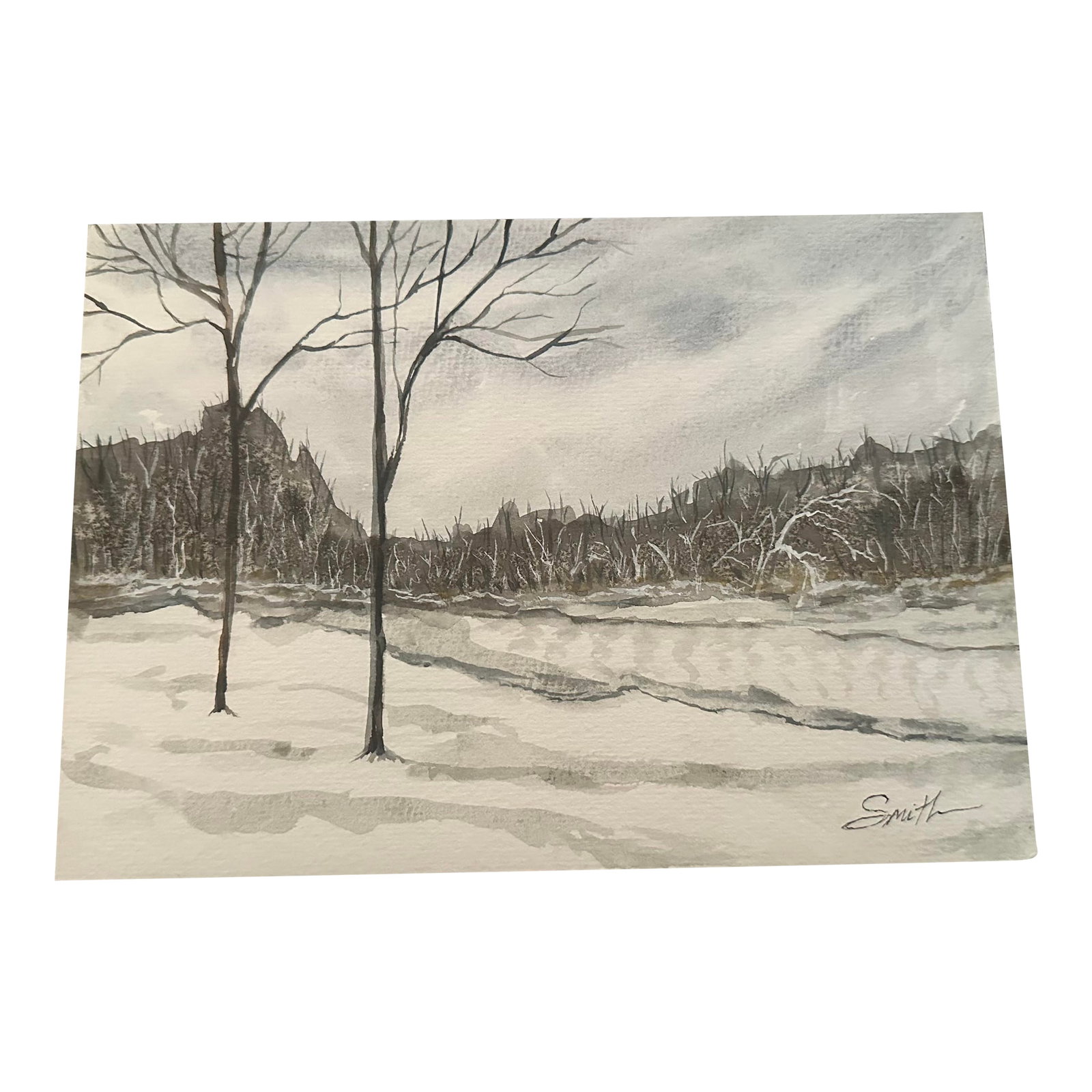 "Cabin View" Signed Original Watercolor by Nancy Smith: This original watercolor captures the stillness of a winter landscape, with bare trees standing against softly layered snow and distant hills. Subtle washes of gray and muted earth tones create a peac