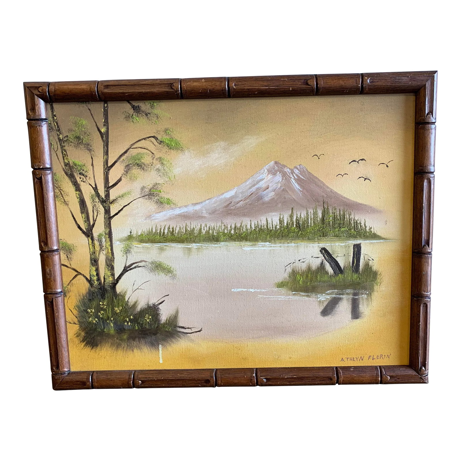 1980 Painting Lake Scene Signed by Artist: Beautiful colors in this Painting of a mountain and lake scene. Signed and dated. The wood frame has a bamboo style to it. Yellow and green tones. Measures 15.5" x 19.5" Condition: Alterations: