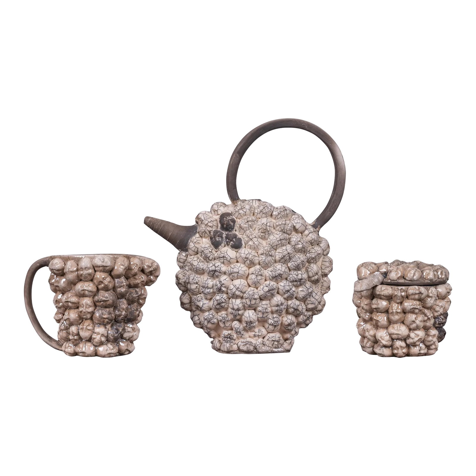 A Doll Head Studio Pottery Tea Set: A doll head raku studio pottery tea set, unsigned. teapot: 10 inches wide by 4 Â½ inches deep by 11 Â½ inches tall sugar and cream approximately 7 inches wide by 5 inches tall.