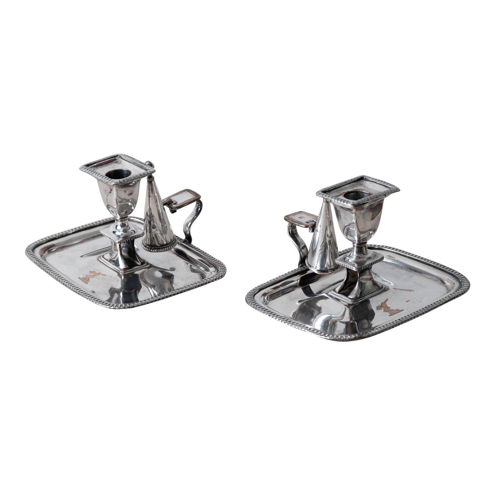 Pair of Old Sheffield Plate Chambersticks, c.1820: Pair of Old Sheffield plate chambersticks with removable nozzles, conical snuffers, and handled drip pans, circa 1820. Each is decorated with a gauntlet and arrow armorial crest on the tray. 7 inches