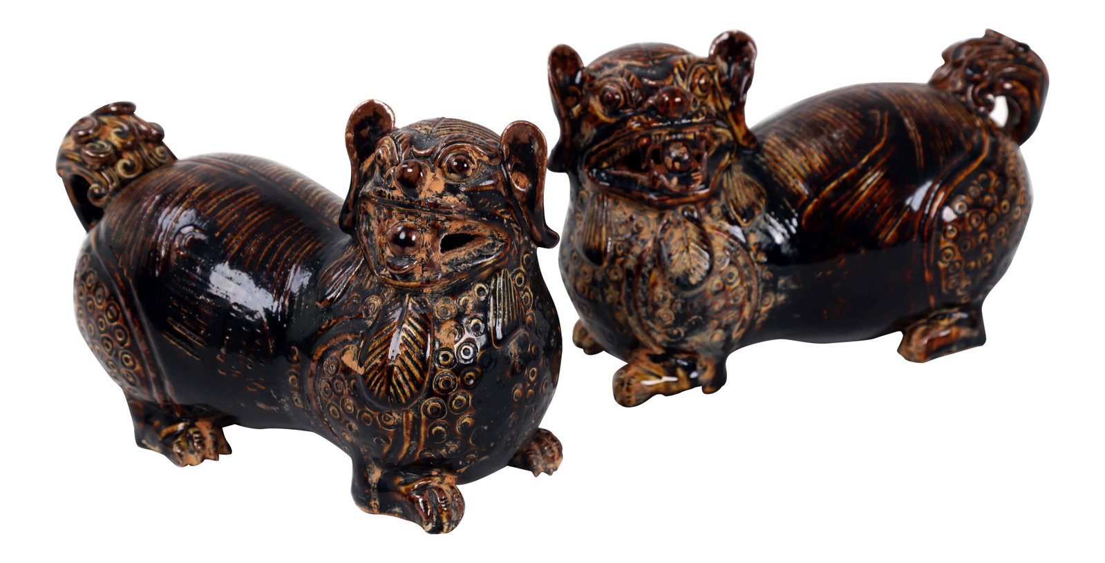 19 Century Antique Porcelain Stoneware Lion Sculptures - a Pair: This lion sculpture is glazed in a dark color with the thin areas showing a bright amber. A ball sits in its jaws, and decorative tassels hang from its neck. sell by pair. Condition: Alterations: