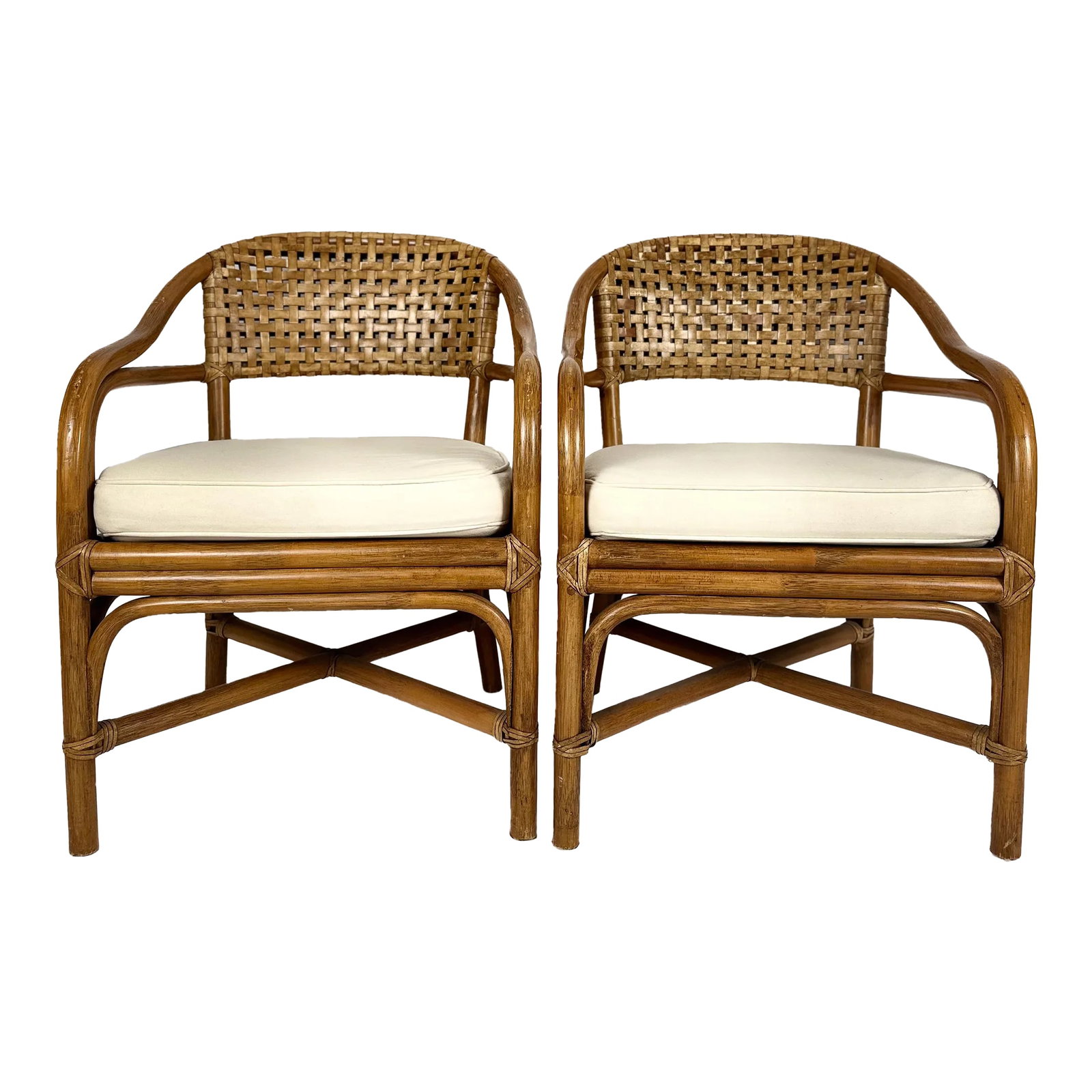 Late 20th Century Pair of McGuire Bamboo Armchairs: We have a beautiful pair of McGuire curved bamboo rattan armchairs with a basketweave leather backrest. Each chair features a soft white linen seat cushion with a fun colorful upholstery underneath.