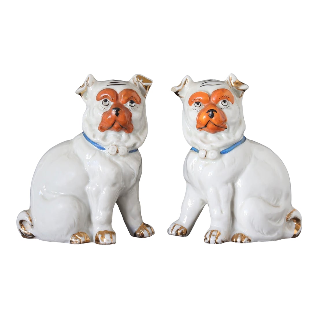 Antique German Porcelain Pugs: This charming pair of antique German porcelain pug figurines features expressive faces with hand-painted orange accents and delicate gold detailing on the paws, collars, and tails. Each pug wears a
