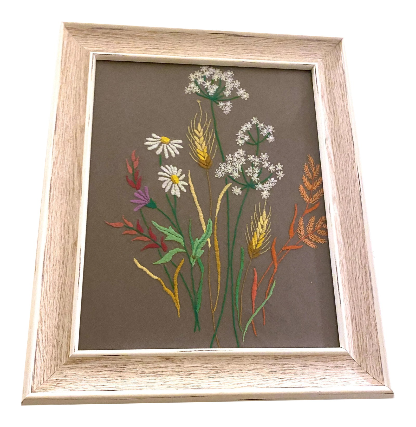 Vintage Mid-Century Daisy Crewel Art: A really pretty bouquet of flowers like babies breath and daisies. Hand stitched on a gray background and framed in a white washed wooden frame. Welcome to Solid Gold Velvet Interiors! We are so