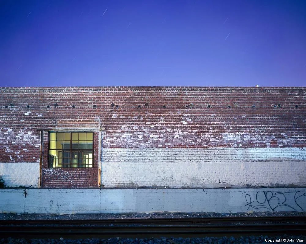 Contemporary Night Photograph "Brick Wall" by John Vias: Note from the artist, John Vias: "I abstracted this scene of railroad tracks, concrete, brick, and sky into colored stripes." This 8" x 10" archival color photograph is presented in a 20" x 16"