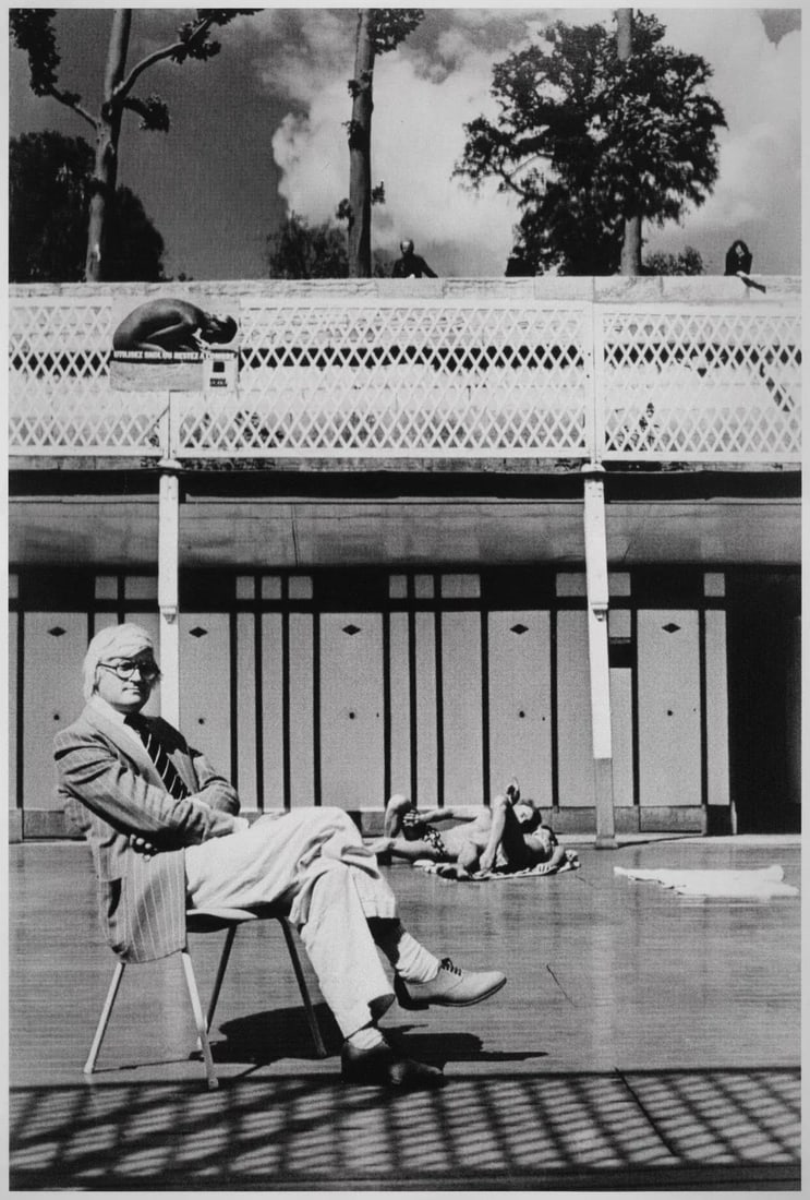 David Hockney, Piscine Royale, Paris 1975 Vintage Silver Gelatin Print by Helmut Newton: David Hockney, Piscine Royale, Paris 1975 20x24 Vintage Silver Gelatin Print by Helmut Newton. David Hockney, famous artist, captured by Newton in a chair with crossed arms and legs. A man and woman