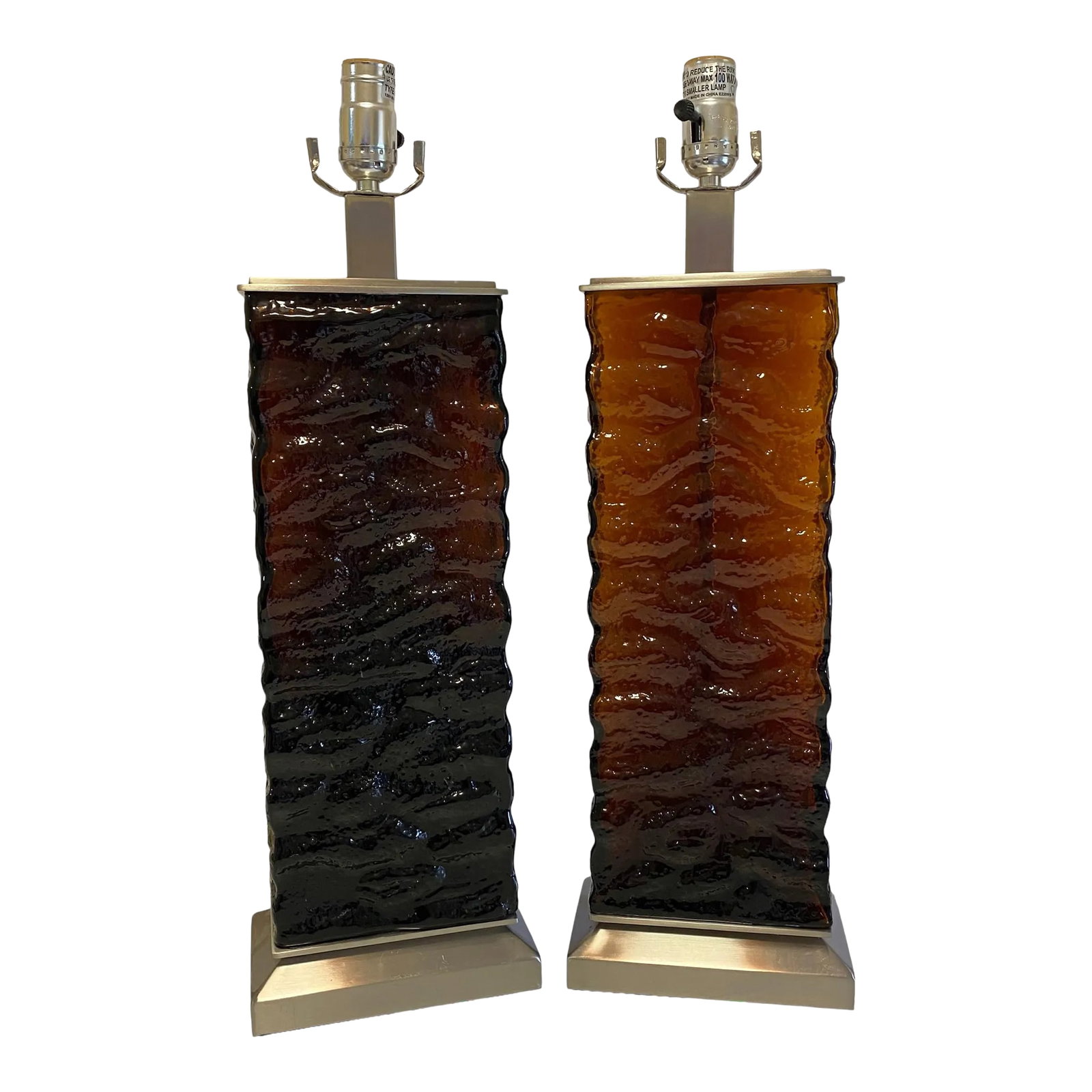 Amber-Brown Textured Wavy Glass Table Lamps in the Mid-Century Modern Taste - A Pair: A dramatic pair of amber glass table lamps that bring warmth, texture, and architectural presence to a room. Rectangular panels of heavily textured amber glass are framed by brushed metal bases and