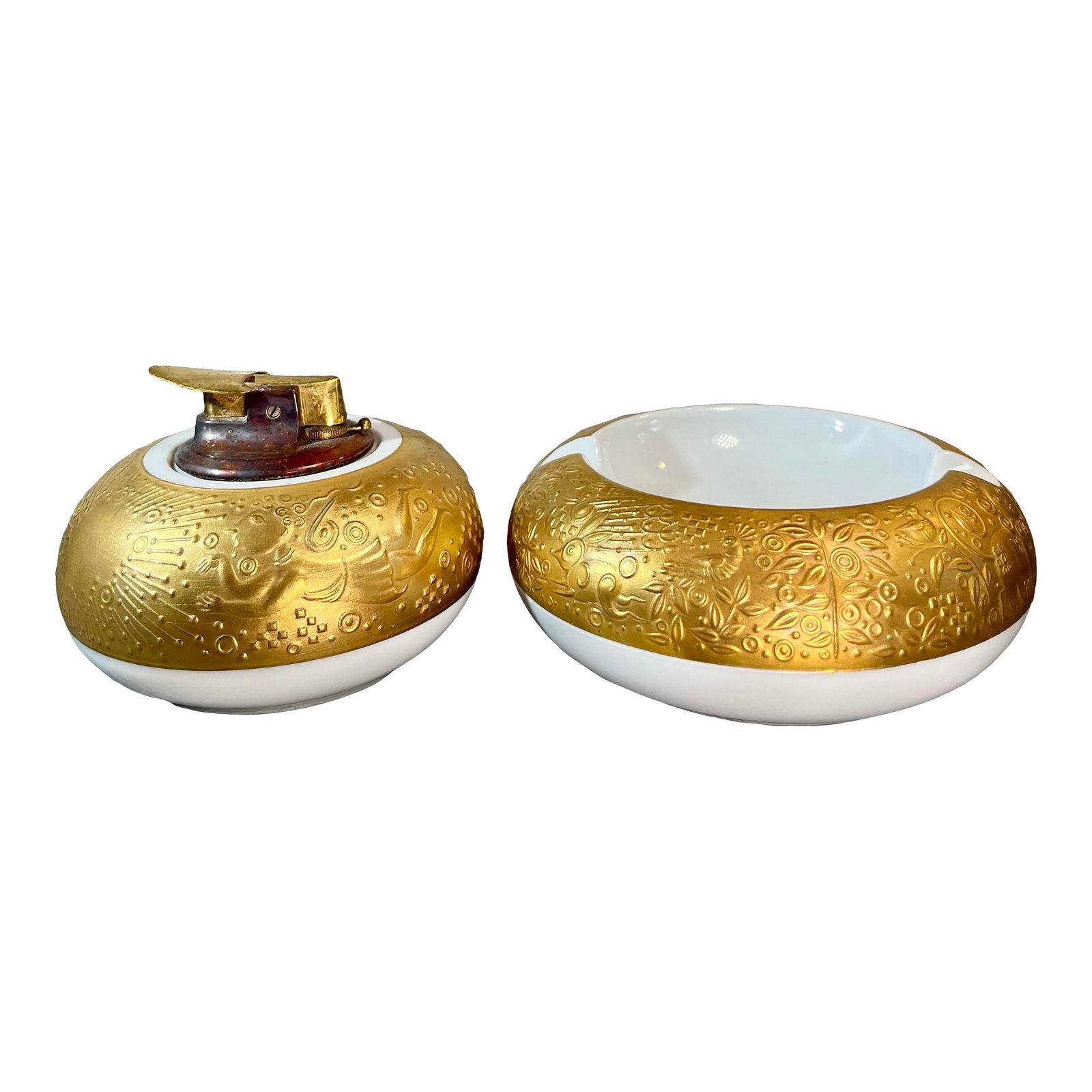 1970s Rosenthal Germany Magic Flute Gold Porcelain Ashtray & Cigarette Lighter- 2 Pieces: Rosenthal Magic Flute gold porcelain ashtray and lighter, designed by Bjorn Winblad. Gold embossed rim, people, birds, and flowers. Underside with printed factory mark and passages from the libretto
