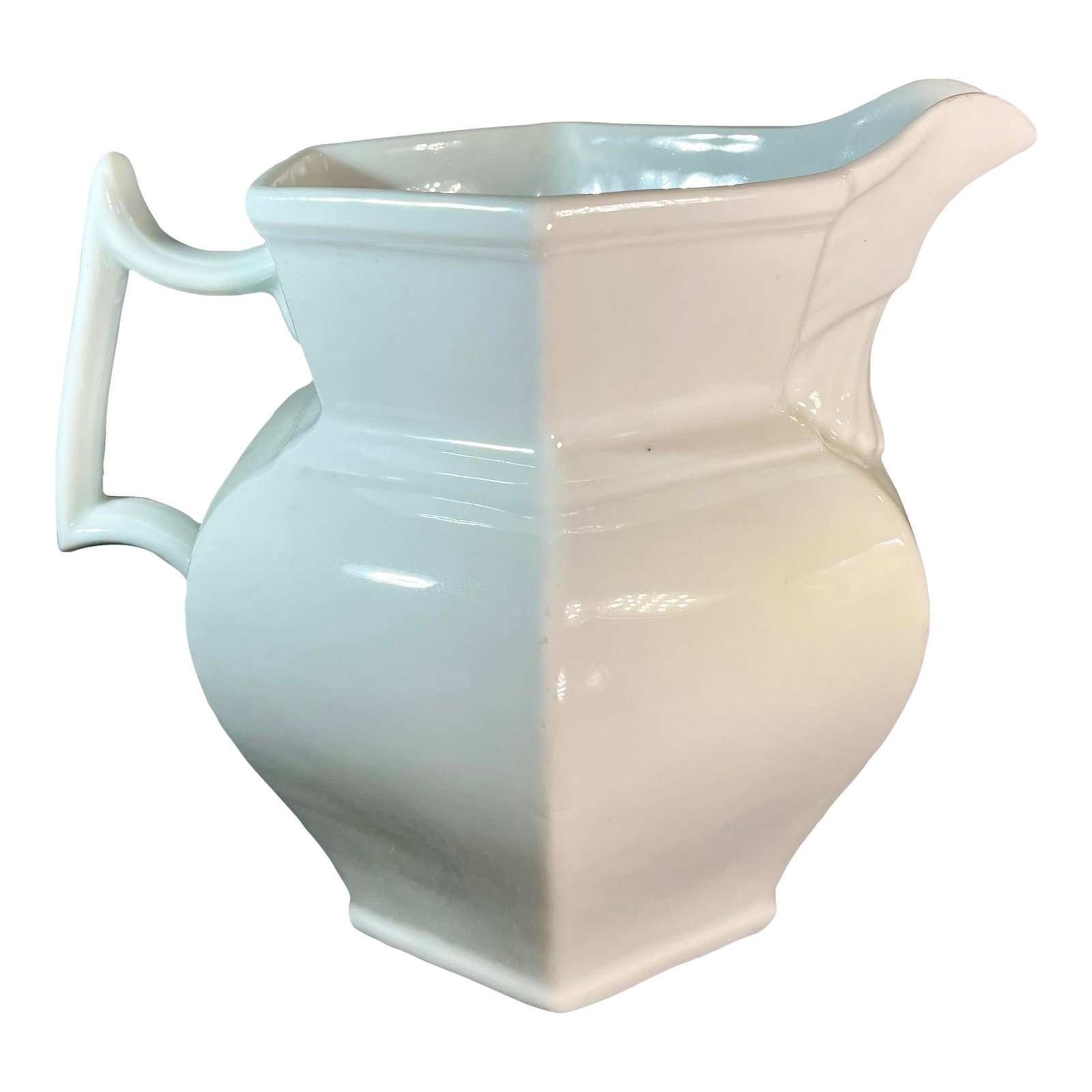 19th Century White Ironstone Pitcher: Classic white glazed pitcher with a paneled shape form and clean line design. Curved shape handle adding a contemporary flare. *Former Property of the Brooklyn Museum. Condition: Alterations: